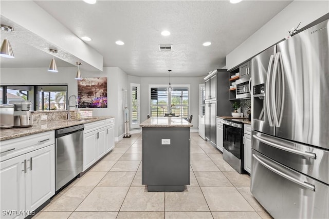 kitchen featuring recessed lighting, stainless steel appliances, a sink, a center island, and a textured ceiling