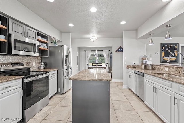 kitchen featuring open shelves, a kitchen island, appliances with stainless steel finishes, and a sink