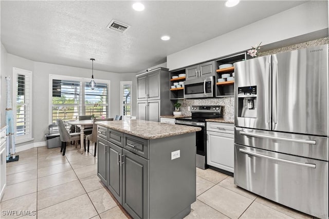 kitchen with open shelves, appliances with stainless steel finishes, gray cabinetry, visible vents, and a kitchen island