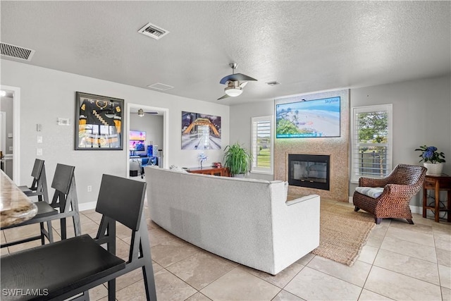 living area featuring a textured ceiling, plenty of natural light, visible vents, and ceiling fan