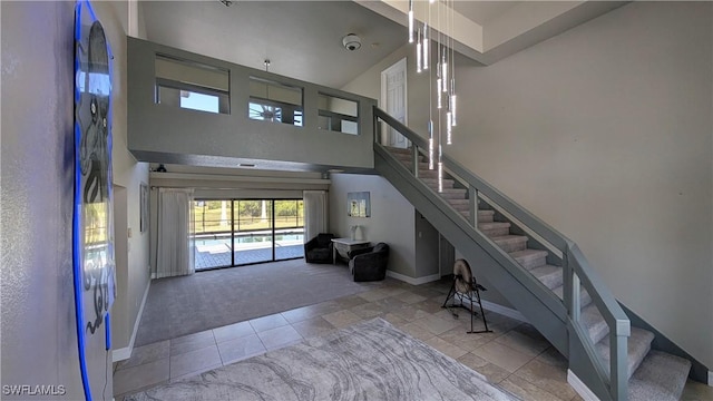 staircase with carpet flooring, baseboards, tile patterned flooring, and a towering ceiling