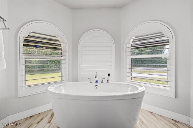 full bath with a soaking tub and baseboards