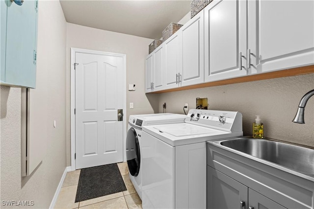 laundry room with a sink, washing machine and dryer, light tile patterned flooring, baseboards, and cabinet space
