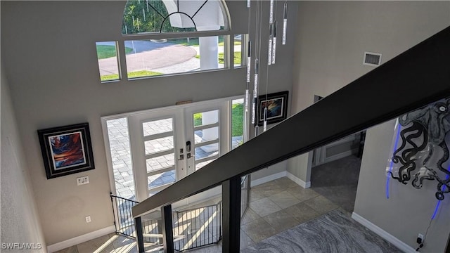 interior space featuring baseboards, french doors, a towering ceiling, and visible vents