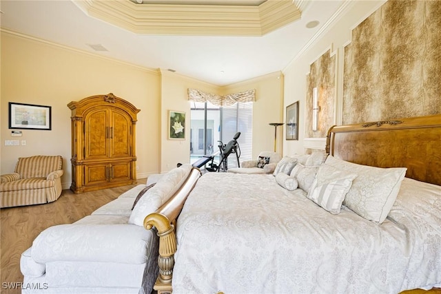 bedroom with crown molding, a tray ceiling, and wood finished floors