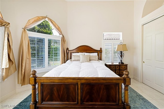 bedroom with multiple windows, light tile patterned floors, and baseboards