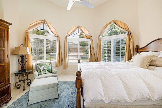 tiled bedroom with a ceiling fan and a towering ceiling