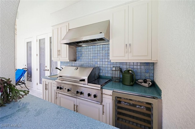 kitchen with wall chimney exhaust hood, wine cooler, decorative backsplash, white cabinets, and a textured wall