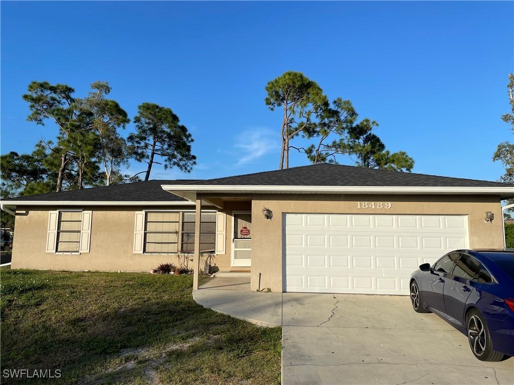 18489 Sunflower Rd, Fort Myers, FL 33967 - ranch-style house featuring stucco siding, an attached garage, a front lawn, and concrete driveway