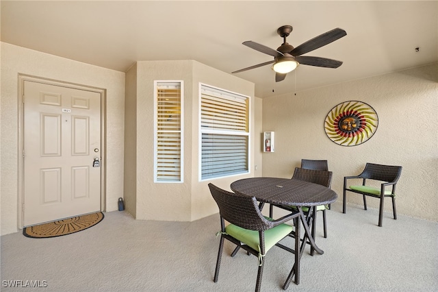 dining room with a textured wall, carpet, and ceiling fan