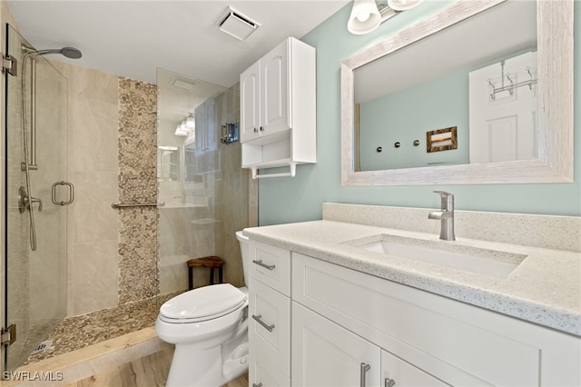 bathroom featuring toilet, visible vents, a shower stall, and vanity