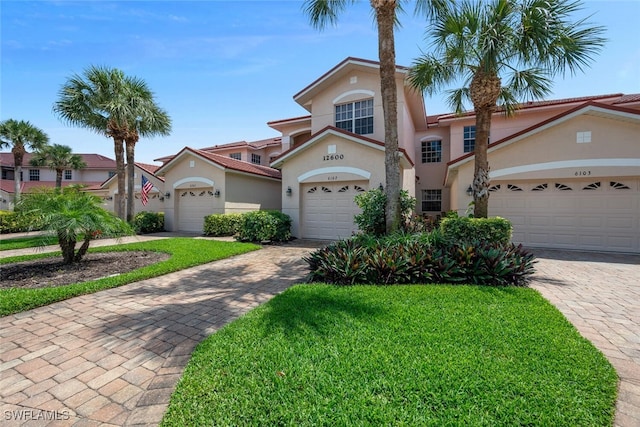 mediterranean / spanish house featuring stucco siding, a front yard, decorative driveway, and a garage