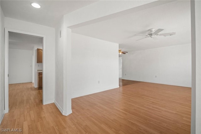 empty room featuring light wood-type flooring, baseboards, and ceiling fan