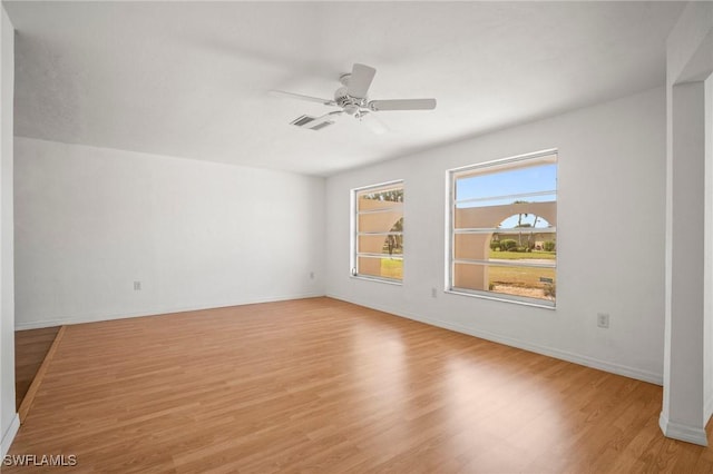 empty room with baseboards, a ceiling fan, light wood-style flooring, and visible vents