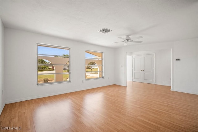 spare room featuring a ceiling fan, baseboards, visible vents, and light wood finished floors