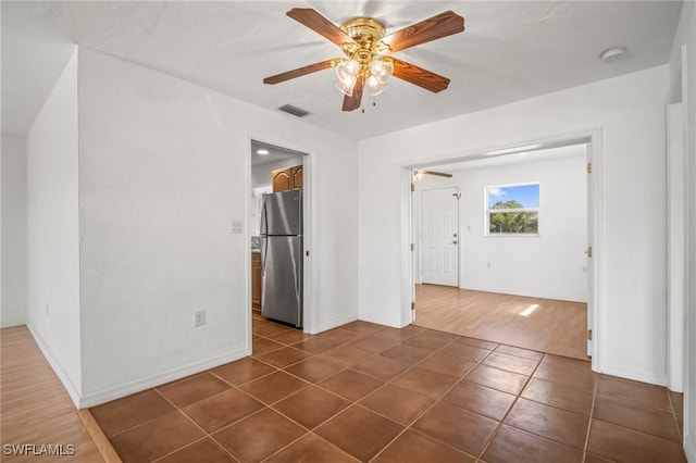 interior space featuring visible vents, a ceiling fan, baseboards, and dark tile patterned flooring