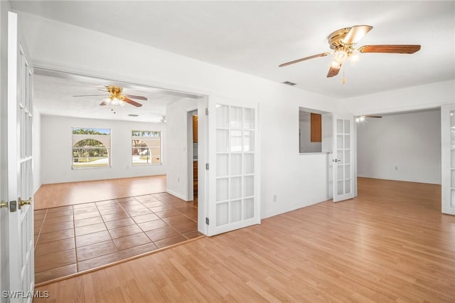 unfurnished room featuring french doors, a ceiling fan, wood finished floors, and visible vents