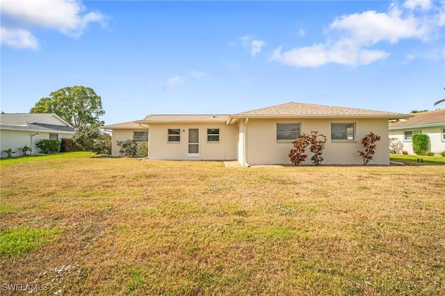 rear view of property with a yard and stucco siding