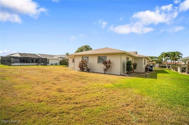 rear view of house with a lawn and stucco siding