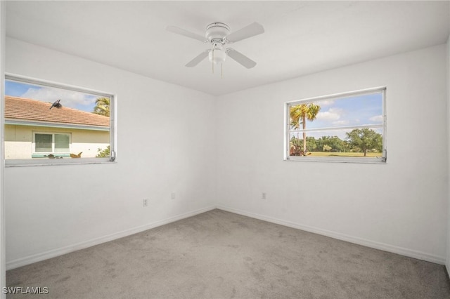 carpeted spare room with baseboards and a ceiling fan