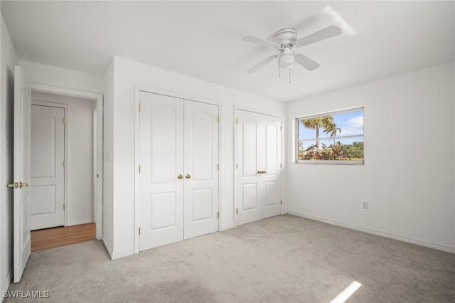 unfurnished bedroom featuring multiple closets, ceiling fan, carpet, and baseboards