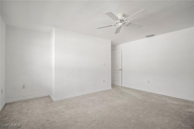 spare room with ceiling fan, visible vents, light carpet, and baseboards