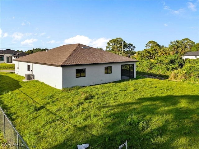 3225 58th St W, Lehigh Acres, FL 33971 - view of side of home featuring central AC unit, a yard, stucco siding, and a shingled roof