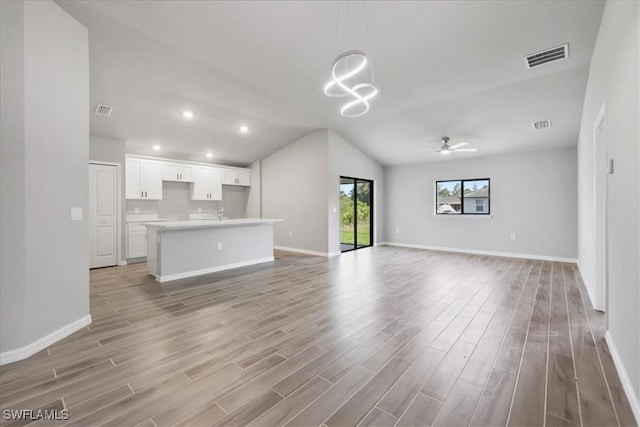 3225 58th St W, Lehigh Acres, FL 33971 - unfurnished living room with ceiling fan with notable chandelier, baseboards, visible vents, and light wood-style floors
