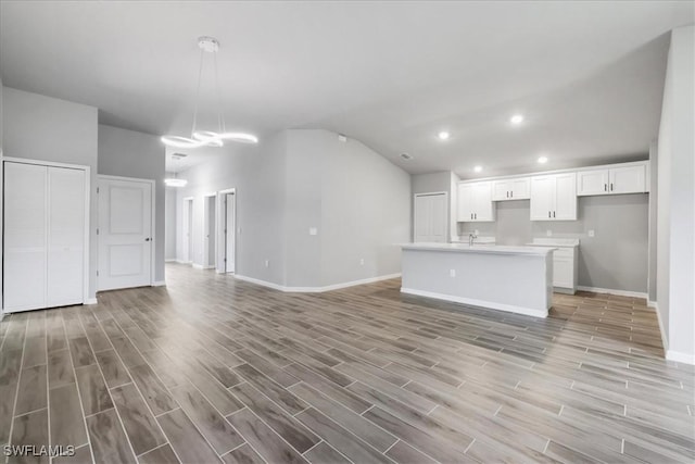 3225 58th St W, Lehigh Acres, FL 33971 - kitchen with white cabinets, baseboards, lofted ceiling, and open floor plan