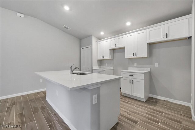 3225 58th St W, Lehigh Acres, FL 33971 - kitchen with a sink, lofted ceiling, a center island with sink, white cabinetry, and wood tiled floor