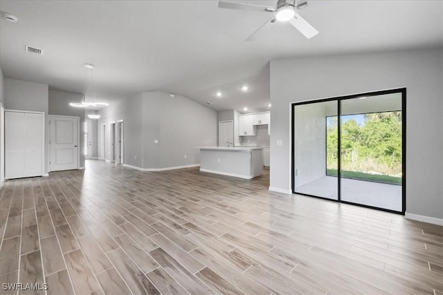 3225 58th St W, Lehigh Acres, FL 33971 - unfurnished living room with light wood finished floors, lofted ceiling, baseboards, and a ceiling fan