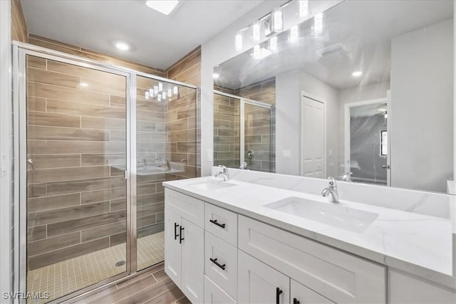 3225 58th St W, Lehigh Acres, FL 33971 - bathroom with wood tiled floor, double vanity, a shower stall, and a sink