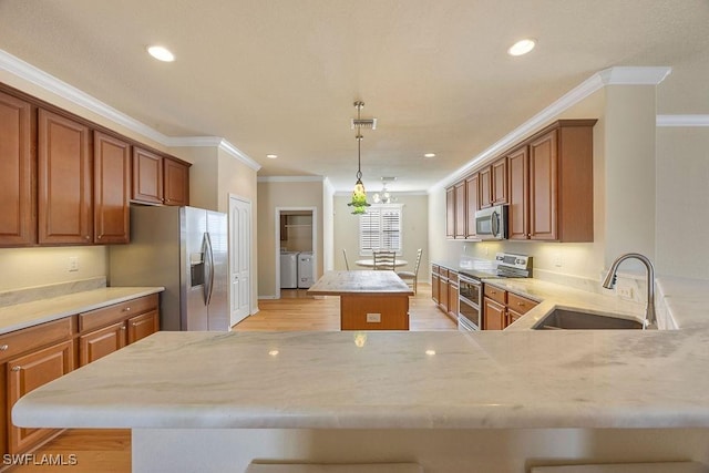 kitchen featuring stainless steel appliances, washer and dryer, a center island, a sink, and crown molding