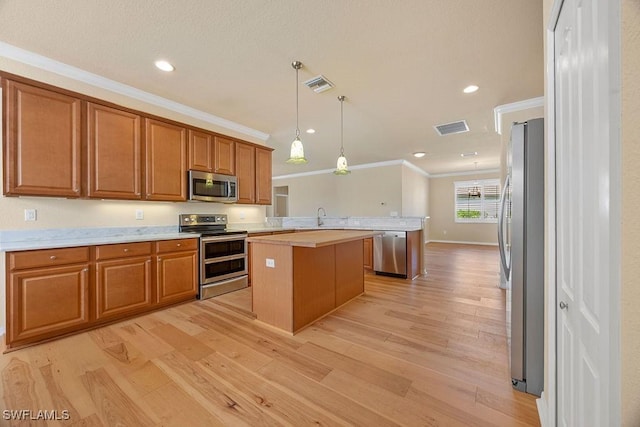 kitchen featuring appliances with stainless steel finishes, ornamental molding, a peninsula, light countertops, and a center island