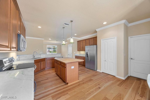 kitchen featuring appliances with stainless steel finishes, a sink, brown cabinets, light wood-style floors, and crown molding