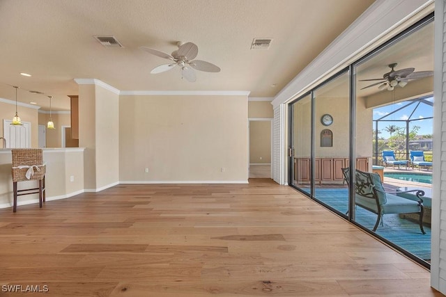 empty room featuring ceiling fan, crown molding, a sunroom, light wood-style flooring, and baseboards