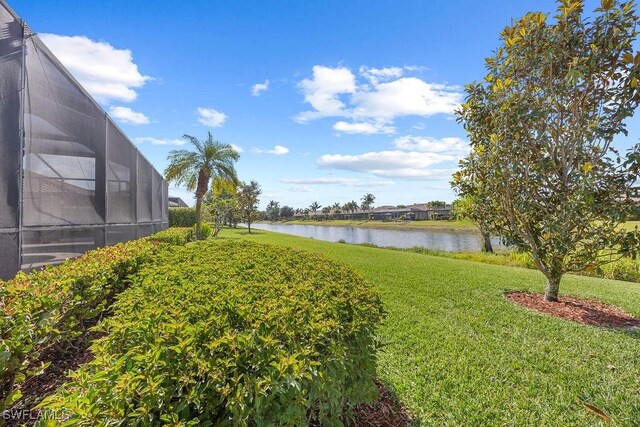 view of green lawn featuring a water view and glass enclosure