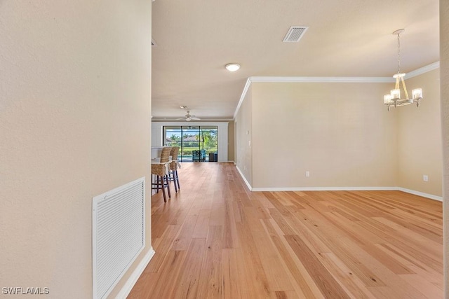 corridor featuring crown molding, light wood-style floors, a chandelier, and baseboards