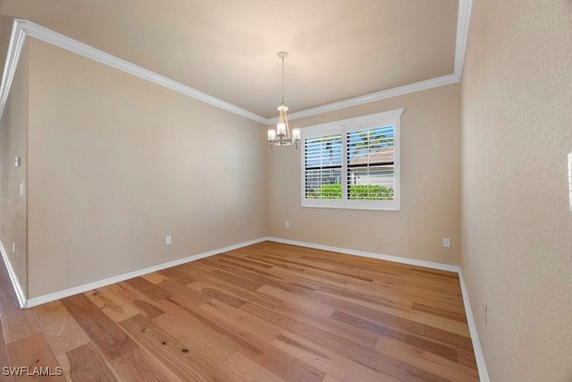 empty room featuring light wood-type flooring, a chandelier, crown molding, and baseboards