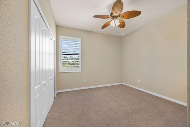 unfurnished bedroom featuring a closet, carpet flooring, baseboards, and ceiling fan