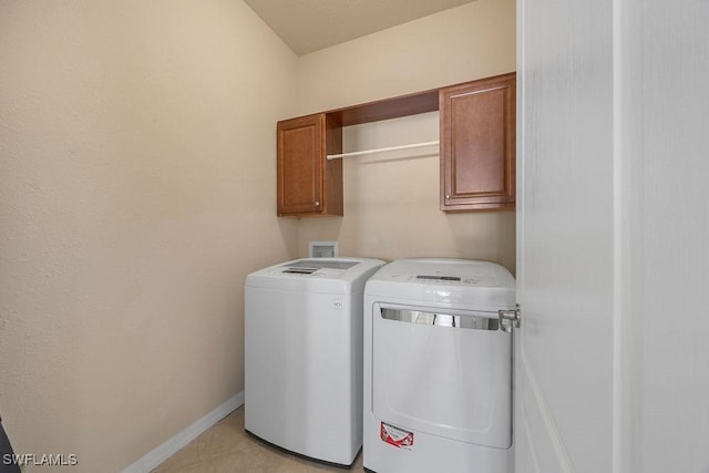 clothes washing area featuring cabinet space, washer and clothes dryer, baseboards, and light tile patterned floors