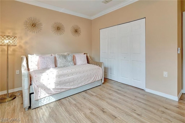 bedroom with wood finished floors, a closet, crown molding, and baseboards