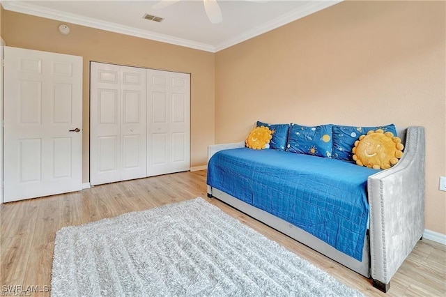 bedroom featuring baseboards, visible vents, wood finished floors, a closet, and crown molding