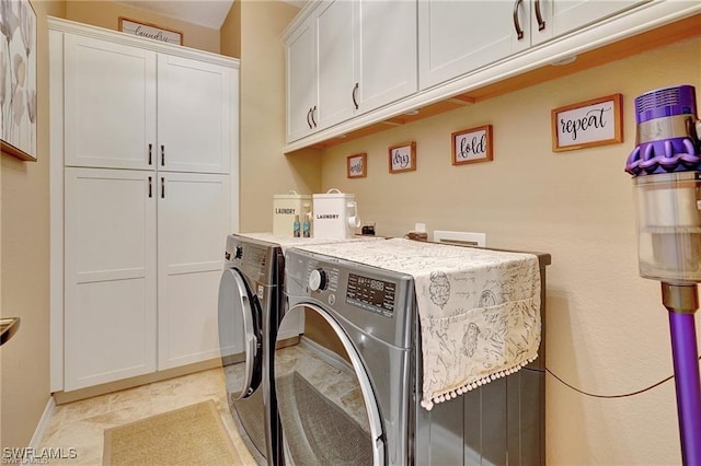 washroom with washing machine and clothes dryer, cabinet space, and baseboards
