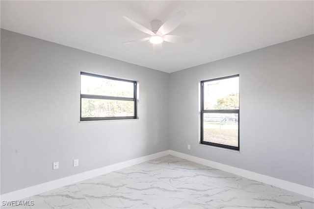 242 Ground Dove Cir, Lehigh Acres, FL 33936 - empty room featuring light marble finish floors, healthy amount of natural light, and baseboards