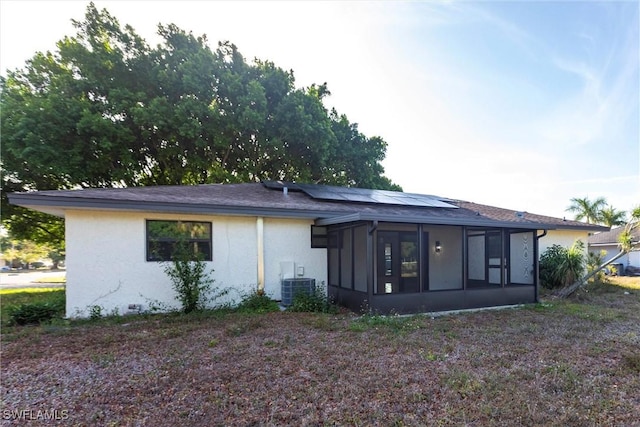 242 Ground Dove Cir, Lehigh Acres, FL 33936 - back of house with a sunroom, roof mounted solar panels, central air condition unit, and stucco siding