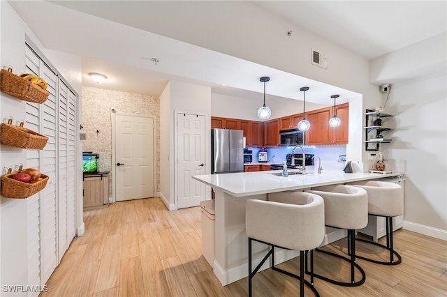 20310 Estero Gardens Cir Unit 102, Estero, FL 33928 - kitchen with a sink, brown cabinetry, stainless steel appliances, a peninsula, and visible vents