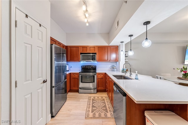 20310 Estero Gardens Cir Unit 102, Estero, FL 33928 - kitchen featuring stainless steel appliances, a peninsula, a sink, and brown cabinetry
