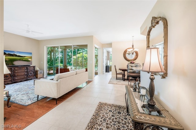 living area featuring a chandelier, light tile patterned floors, and baseboards