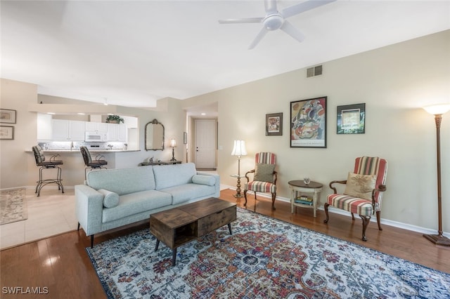 living room featuring ceiling fan, baseboards, and wood finished floors